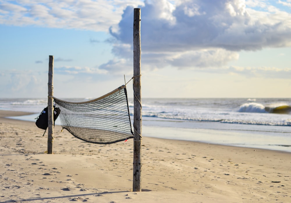 a hammock hanging from a wooden post on a beach
