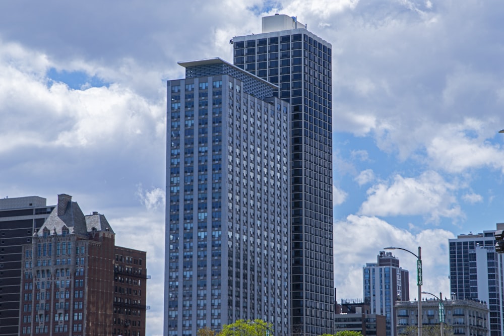 a city skyline with tall buildings and a cloudy blue sky