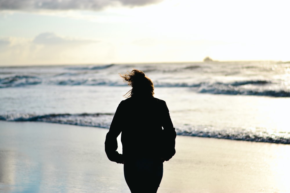 a woman walking on the beach at sunset