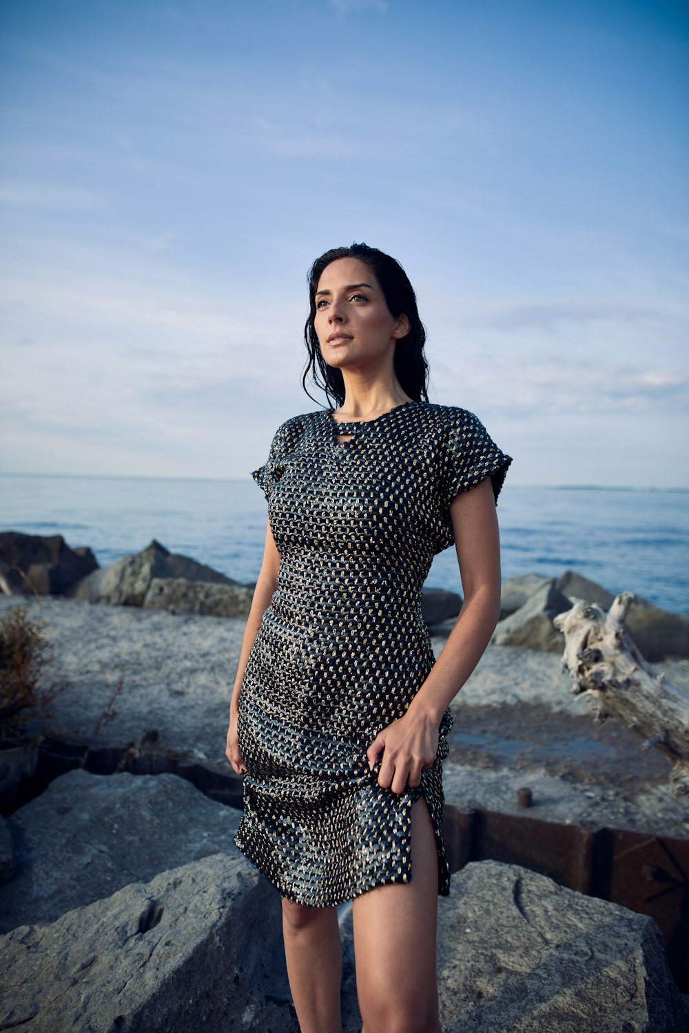 uma mulher de pé em uma rocha perto do oceano