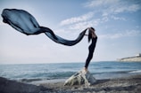 a woman standing on top of a rock near the ocean