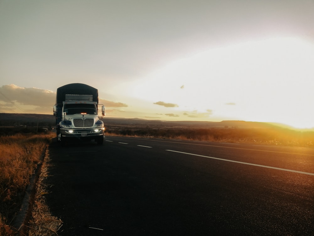 a semi truck driving down a road at sunset