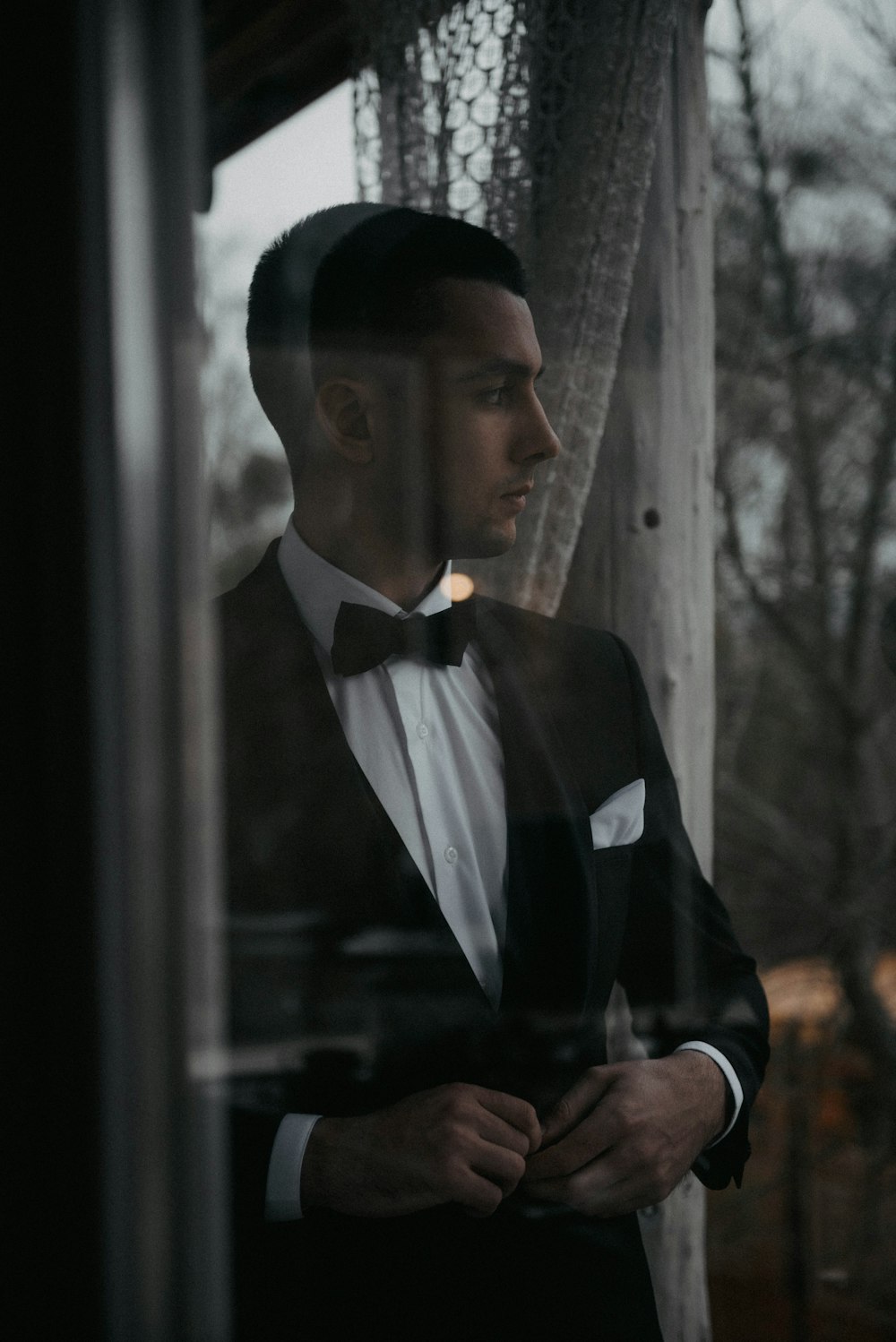 a man in a tuxedo looking out a window