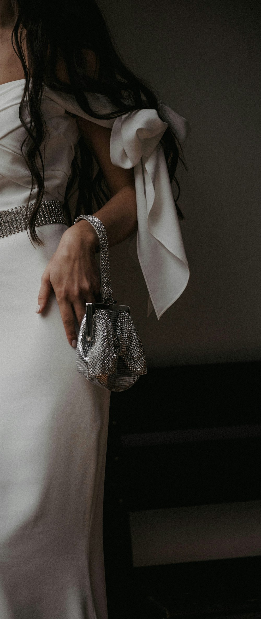 Una mujer con un vestido blanco sosteniendo un bolso