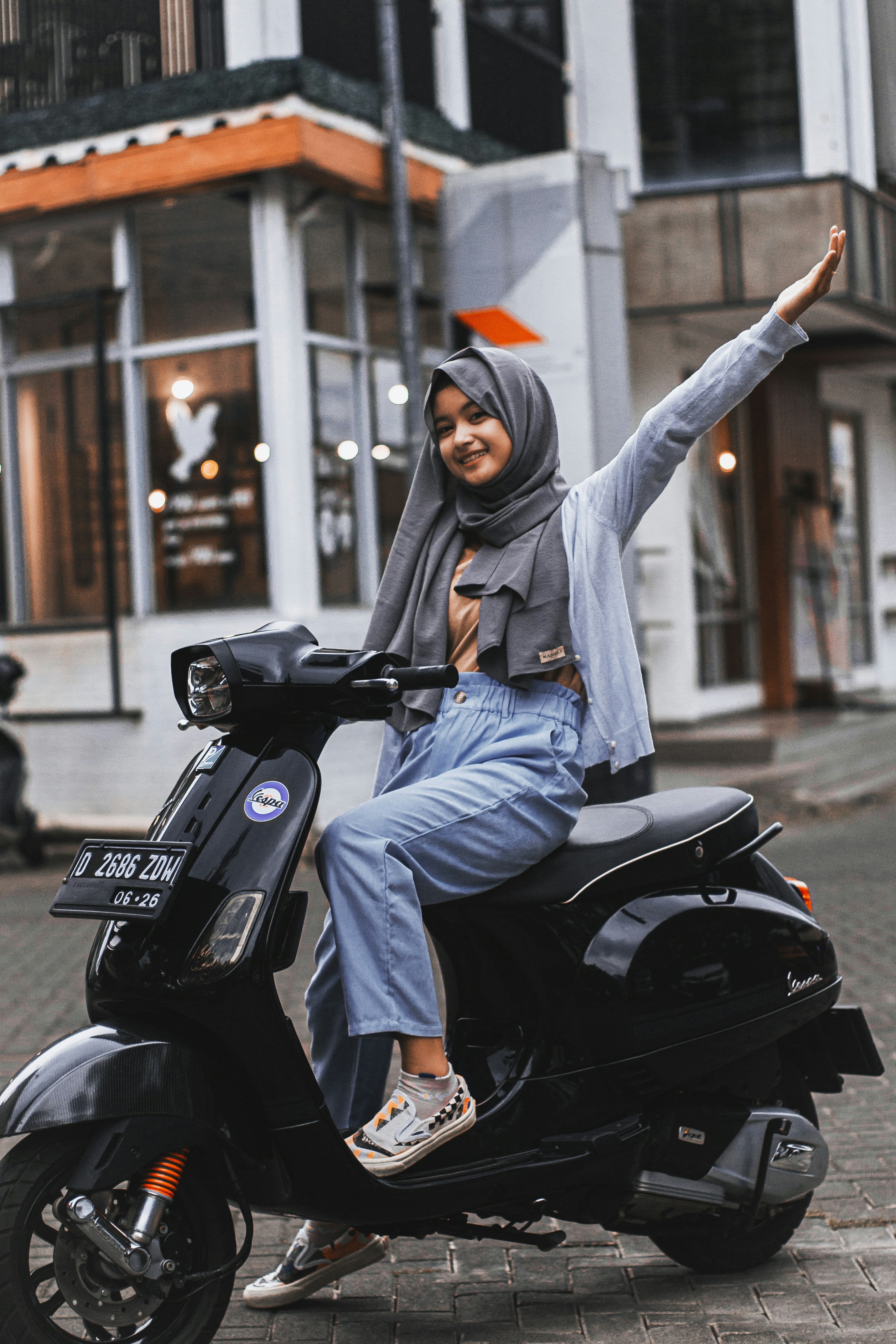 seorang wanita mengendarai bagian belakang skuter hitam