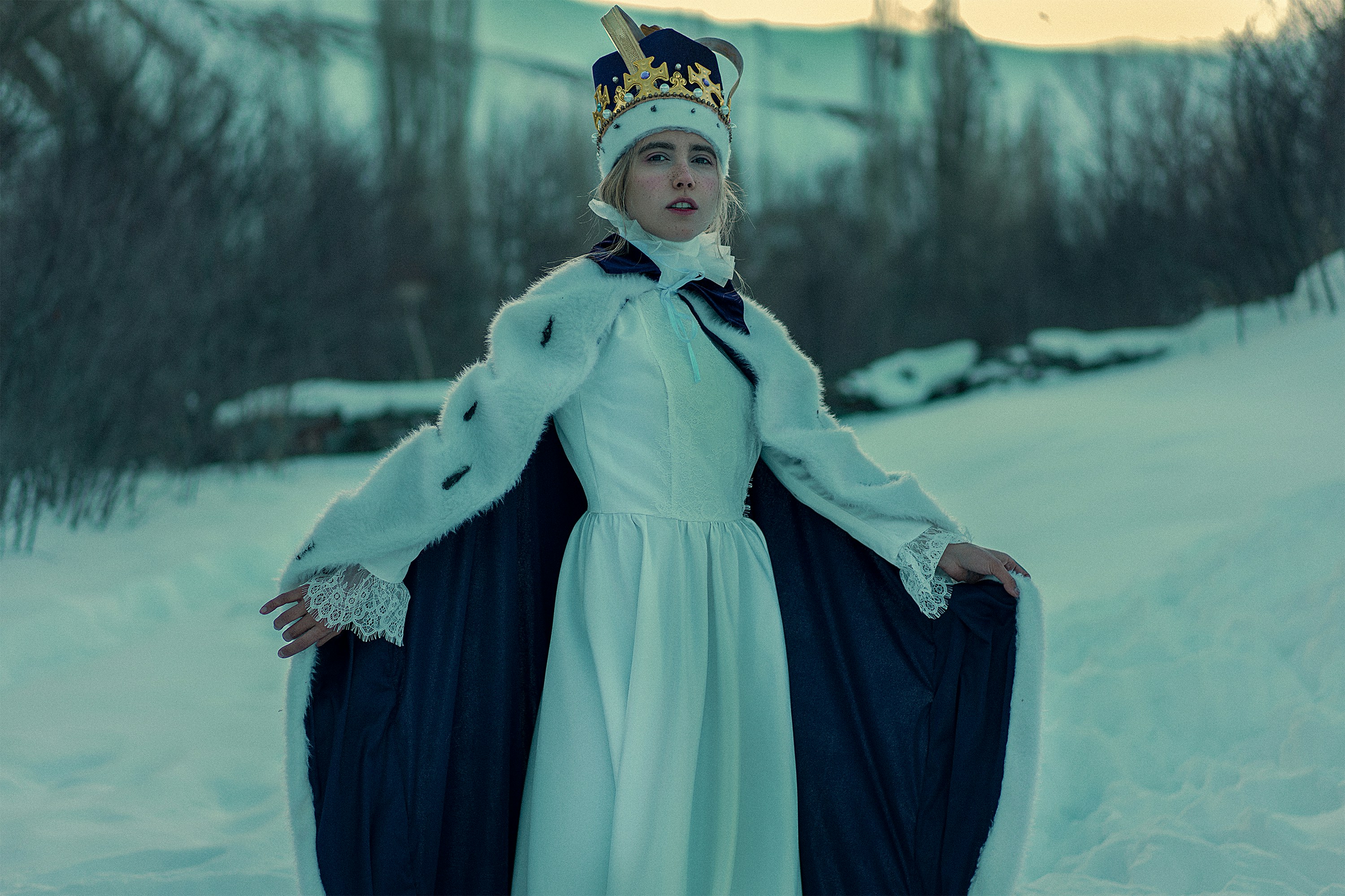Une femme en robe blanche et couronne debout dans la neige