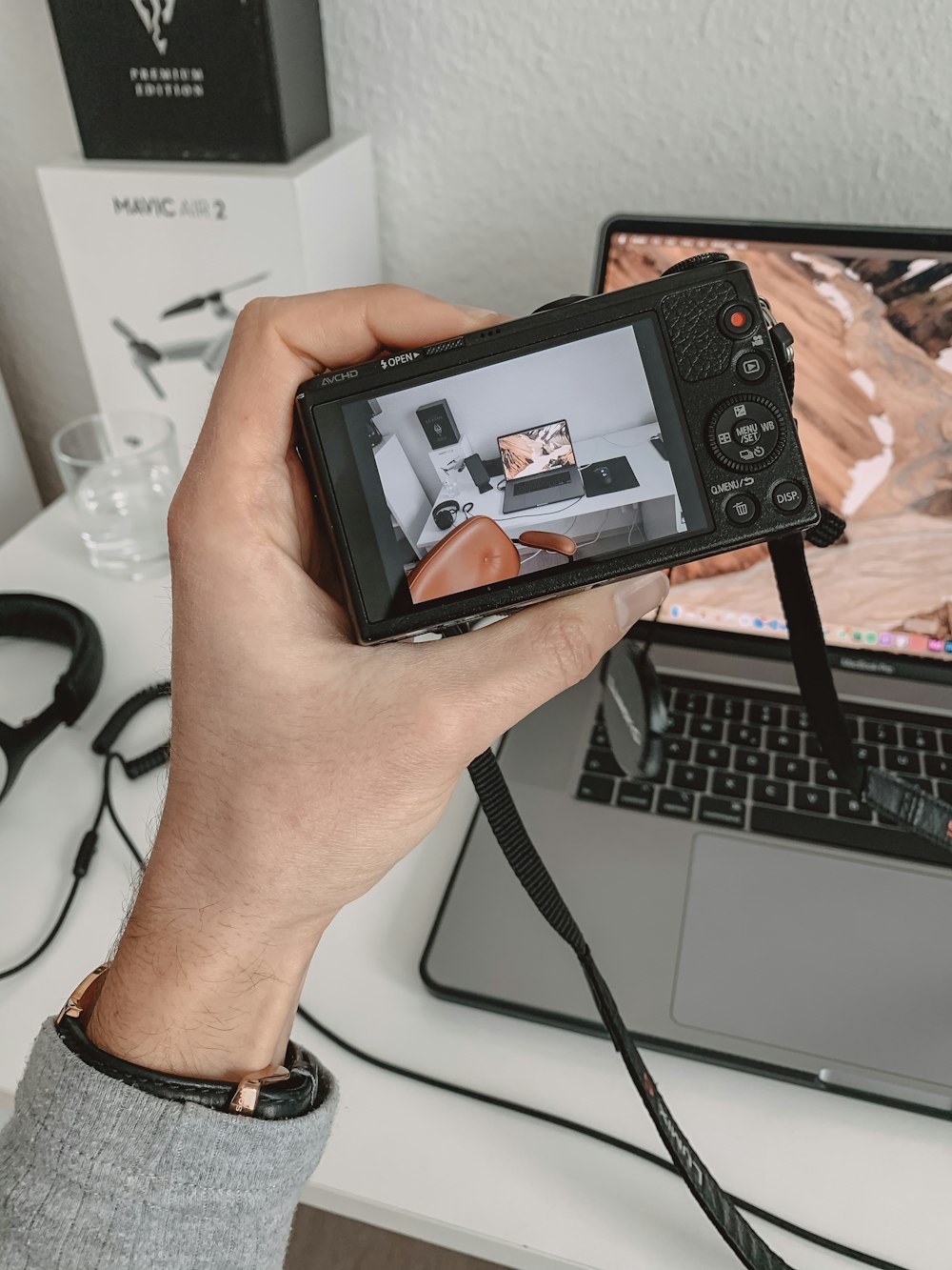 a person holding a camera in front of a laptop