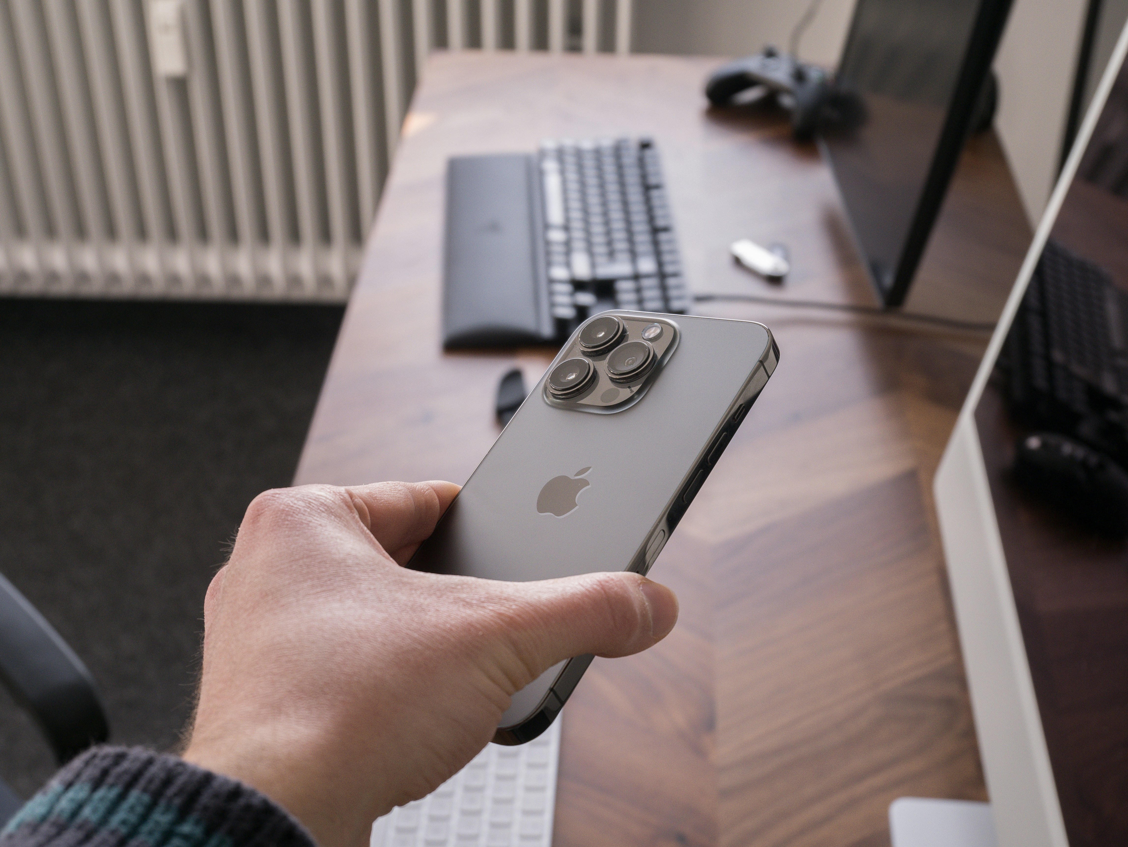 a person holding an iphone in front of a computer