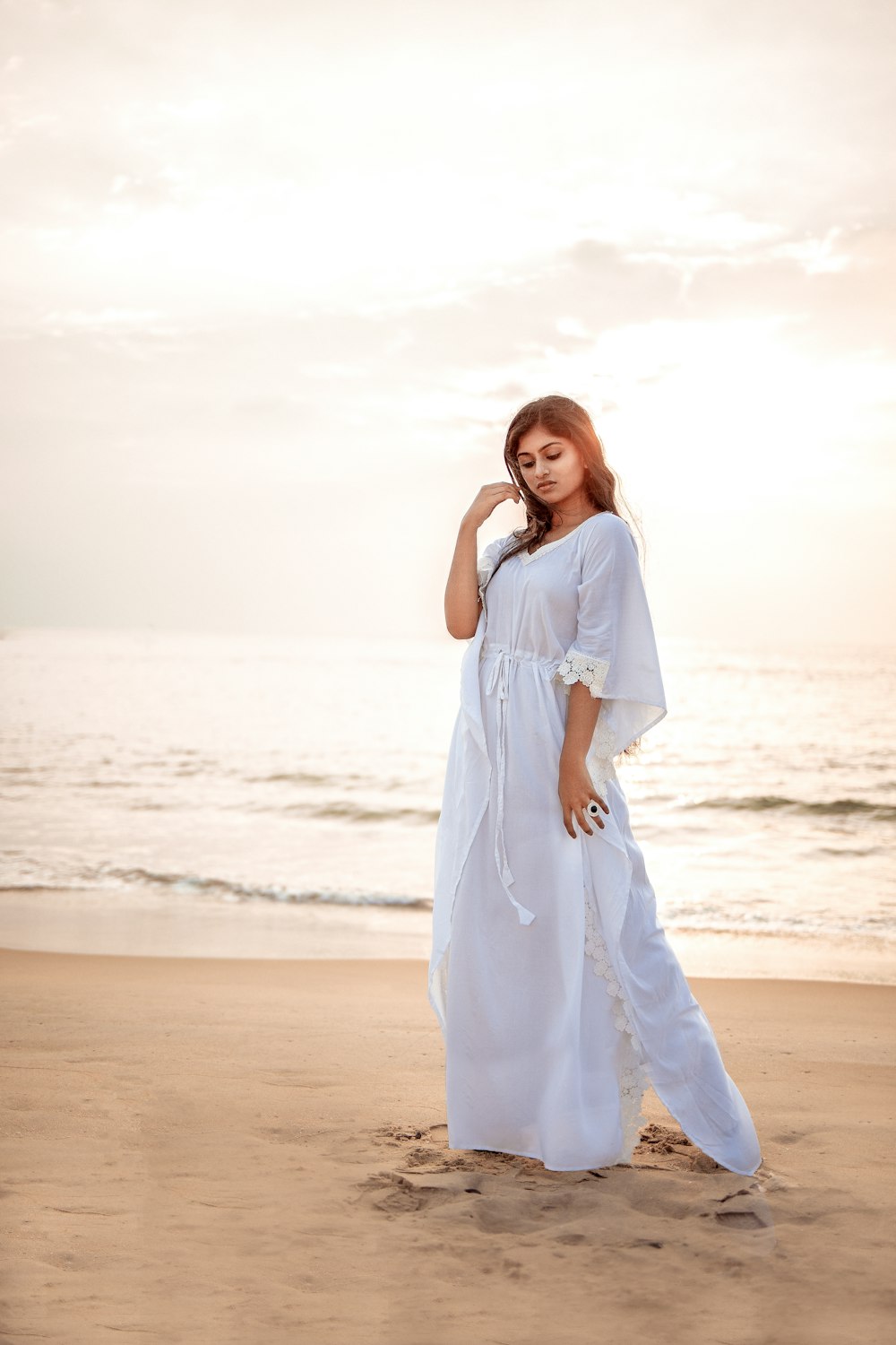 a woman in a white dress standing on a beach
