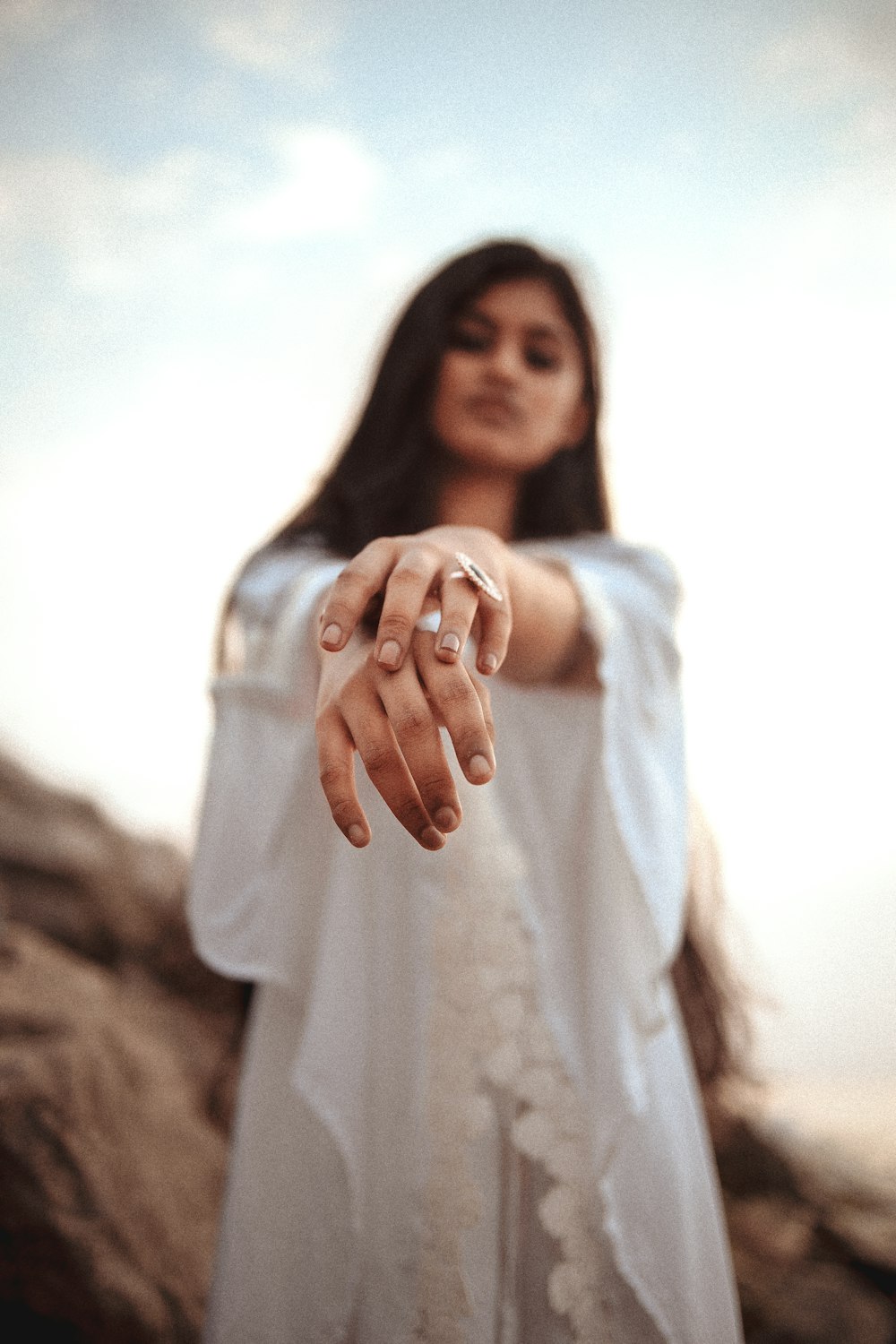 a woman in a white dress holding out her hand