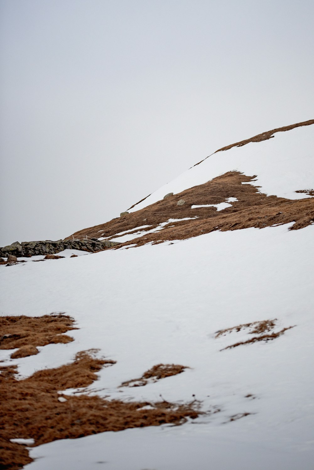 a lone snowboarder is going down a snowy hill