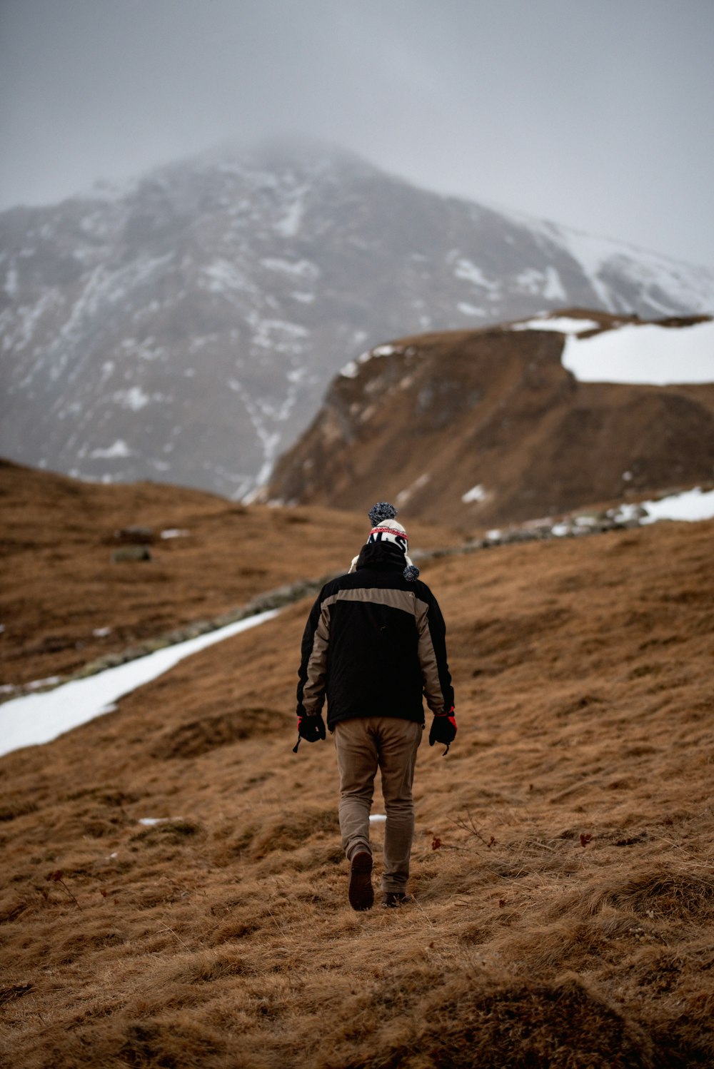 Un homme marchant sur une colline avec une montagne enneigée en arrière-plan