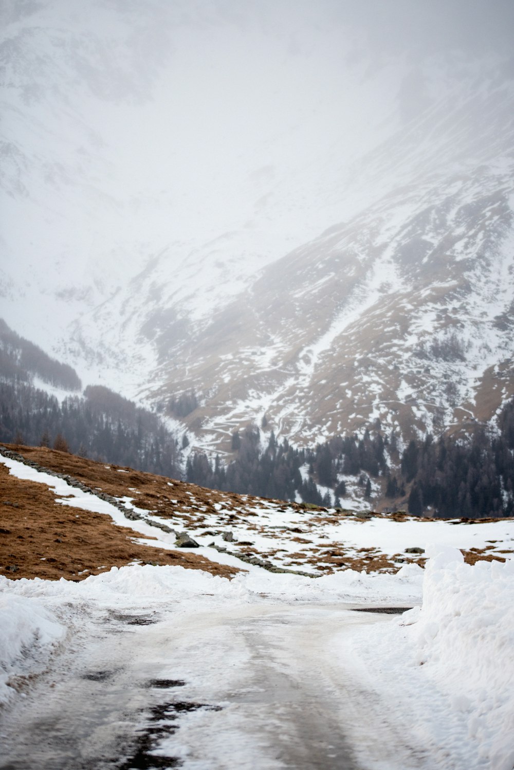 a snow covered road with a mountain in the background