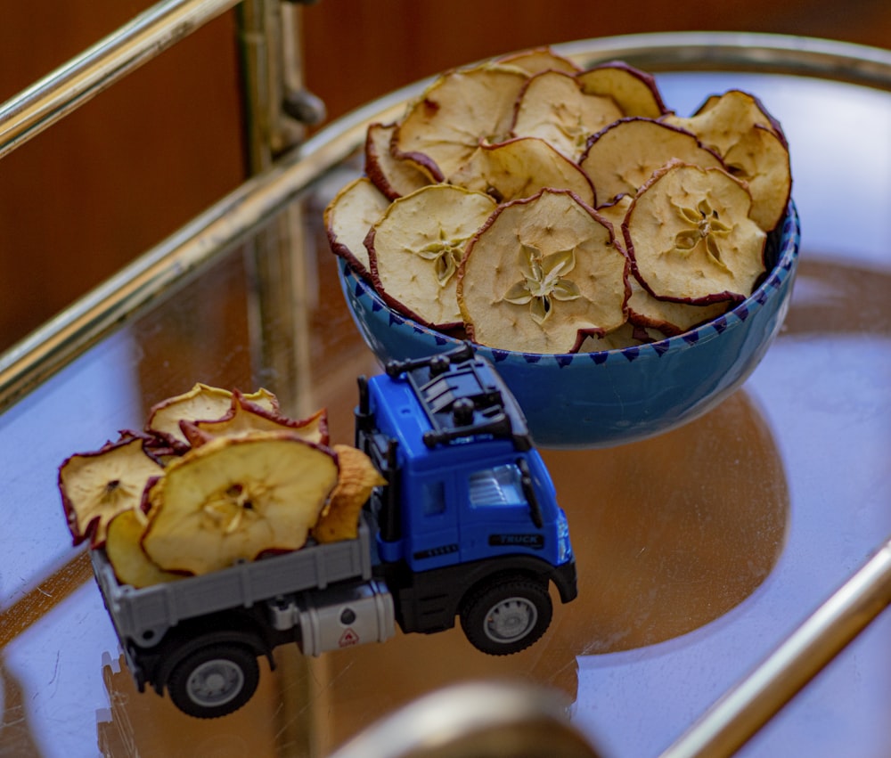 a bowl of apples and a toy truck on a table