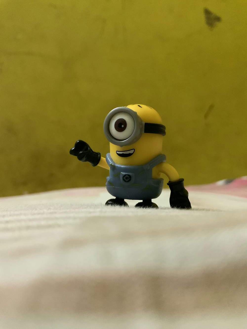 a toy minion is standing on a bed