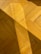 A wooden parquet floor with a diagonal shadow cast across its surface. The wood appears polished, with visible grains and a warm yellow hue. The shadow adds contrast and depth to the image.