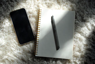 a notepad, pen, and phone on a fluffy surface