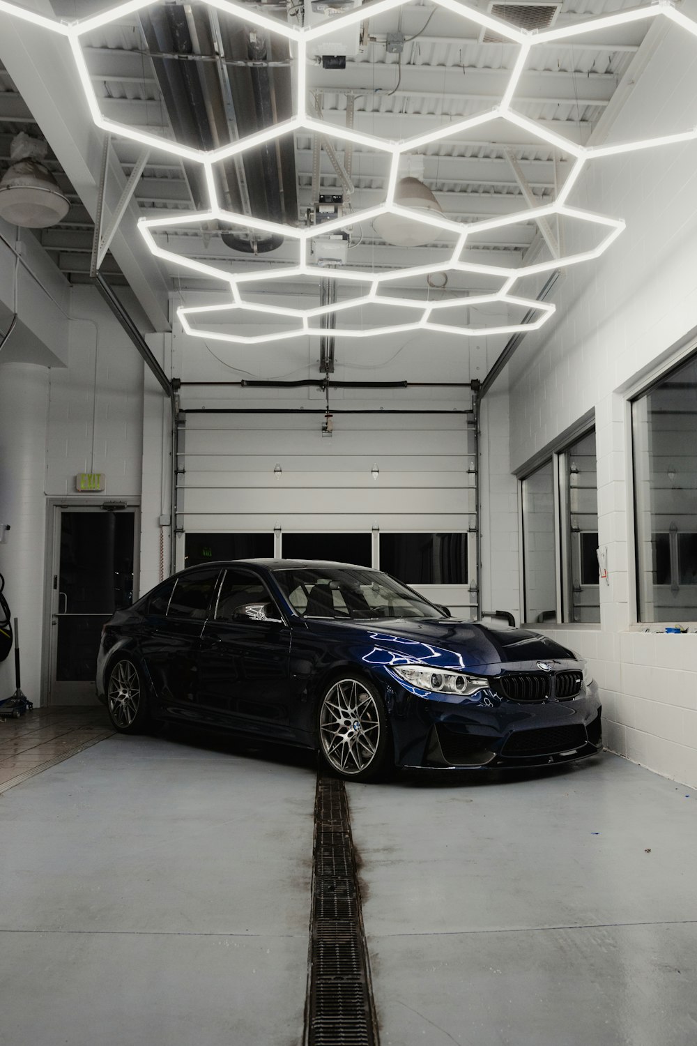 a black car parked in a garage under a light fixture