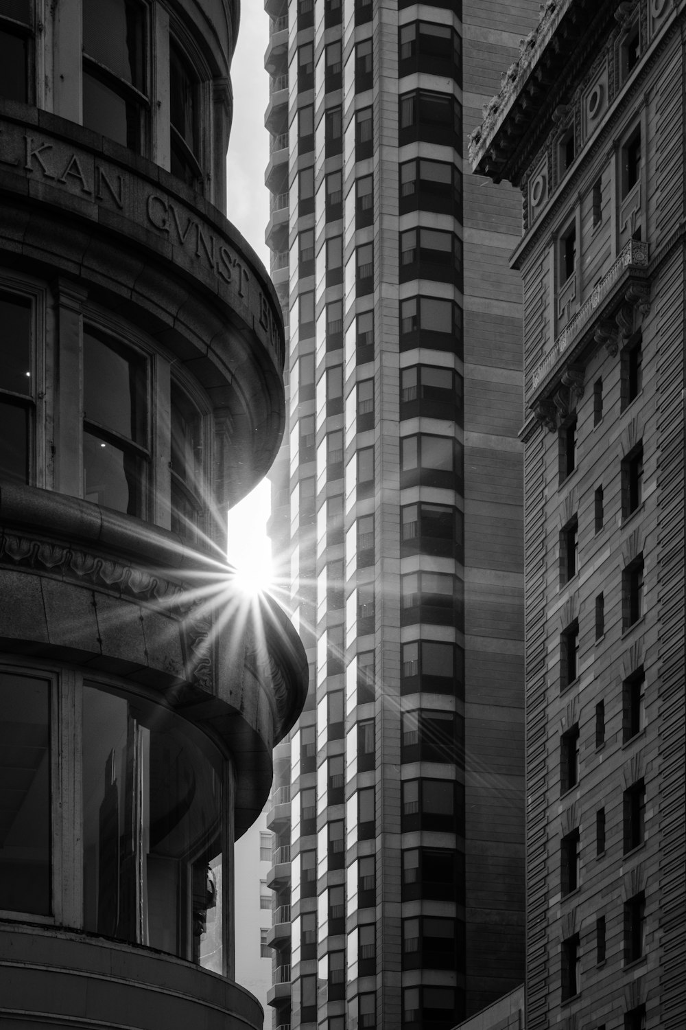 a black and white photo of a building with the sun shining through the windows