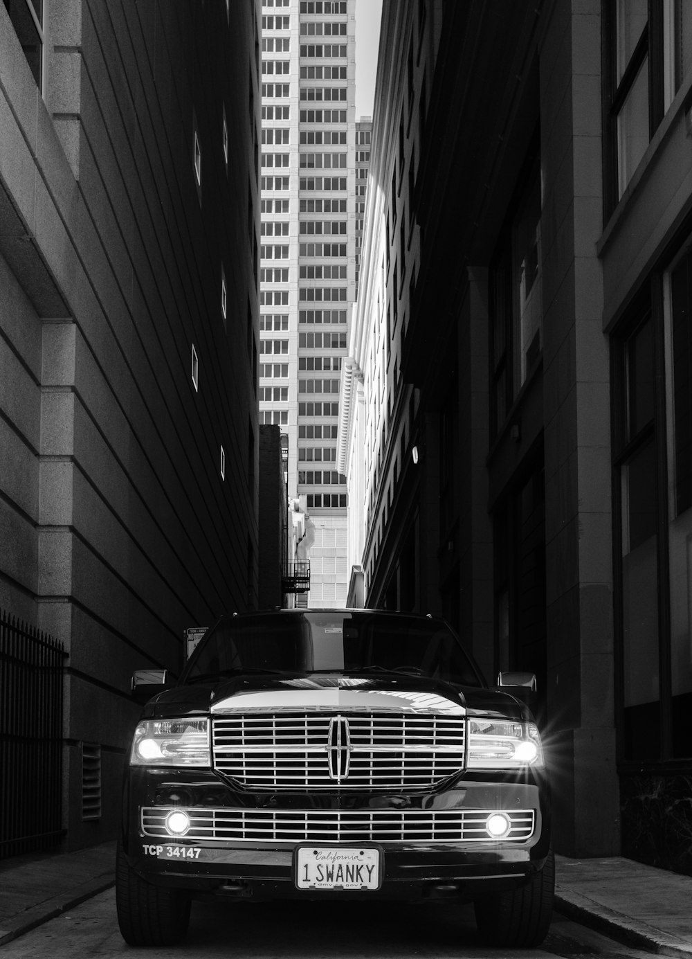 a black and white photo of a car on a city street