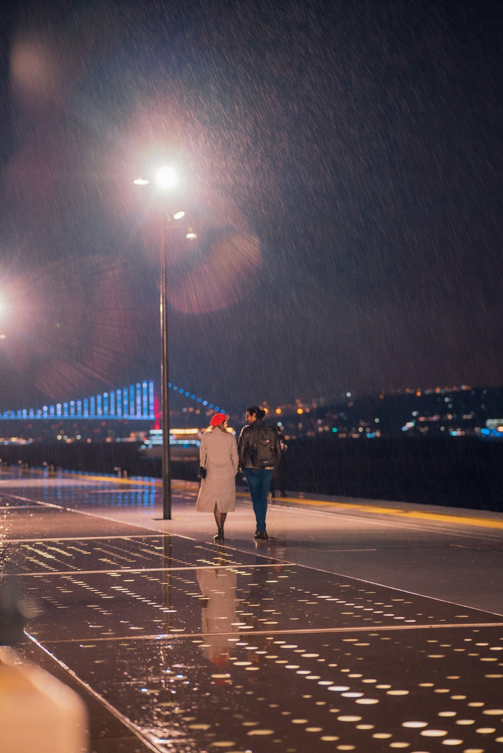 a couple of people walking down a street at night