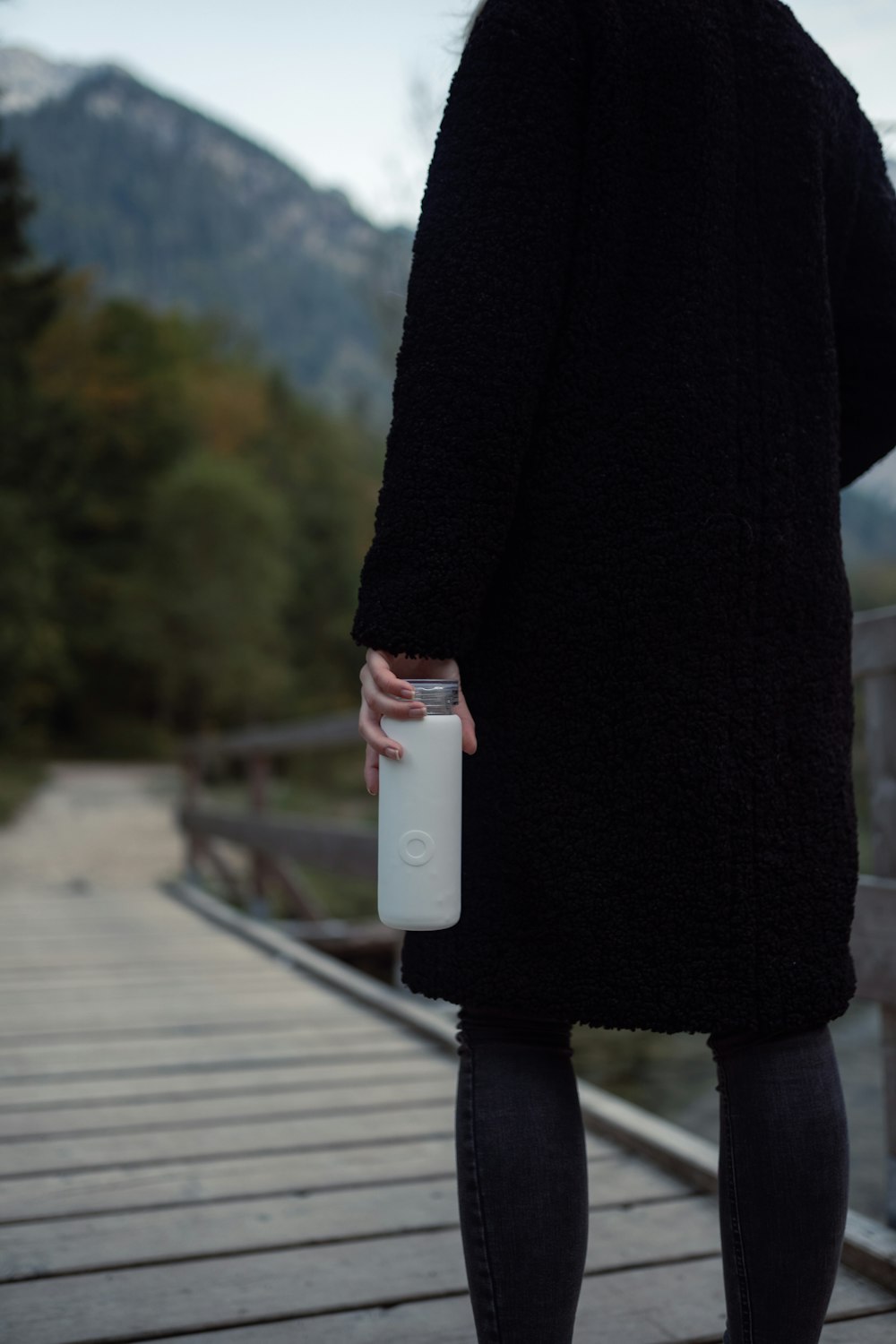 a person standing on a bridge holding a water bottle