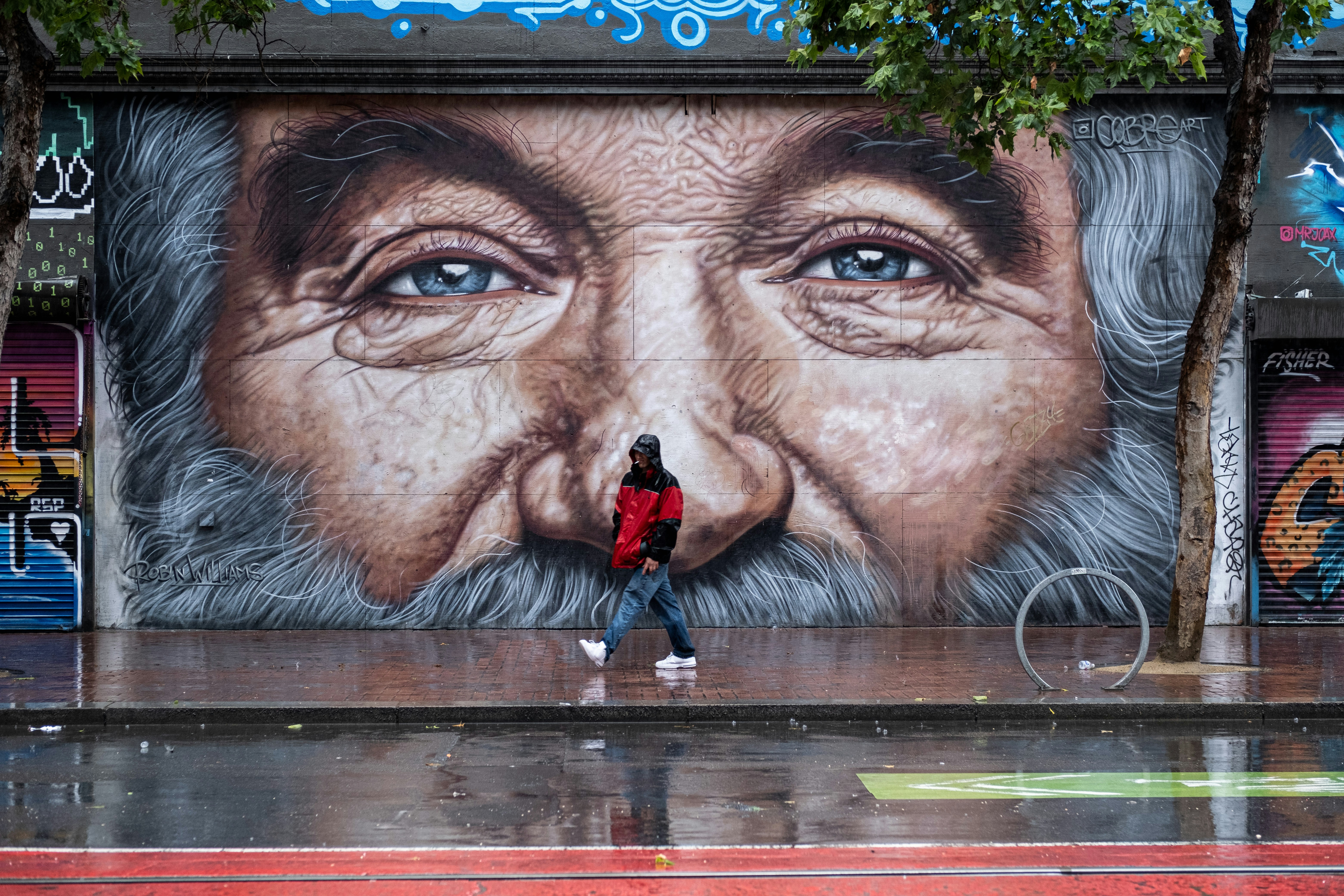 a man standing in front of a mural of an old man