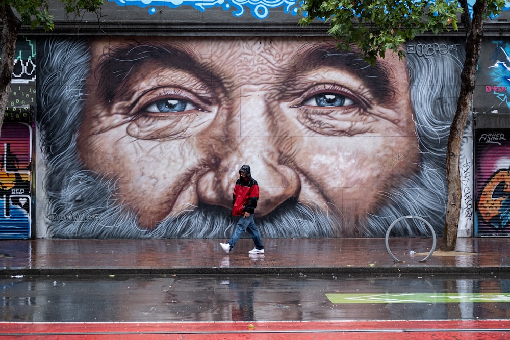a man standing in front of a mural of an old man