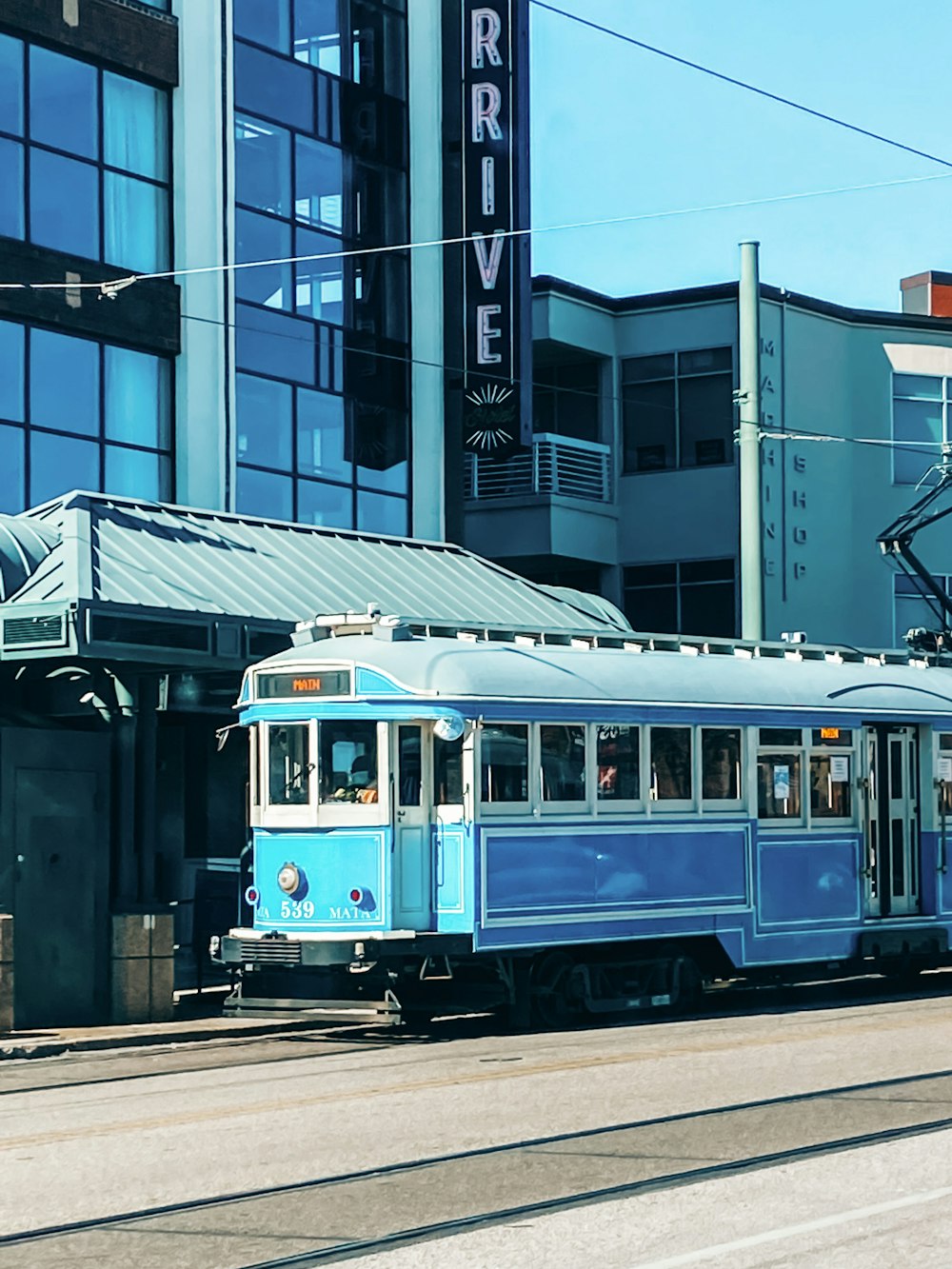 a blue trolley car traveling past a tall building