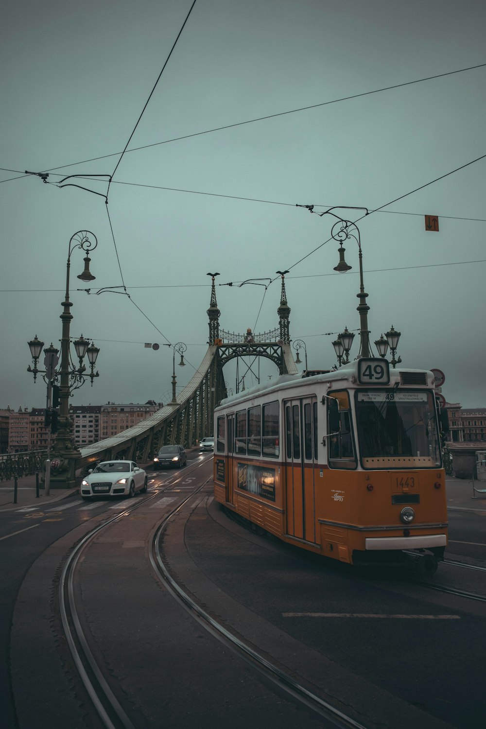 a yellow bus driving down a street next to a bridge