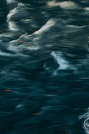 Swirling, turbulent water with patterns of waves and eddies. The surface movement creates a dynamic, fluid appearance.