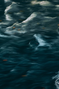 Swirling, turbulent water with patterns of waves and eddies. The surface movement creates a dynamic, fluid appearance.
