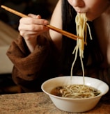 A happy person enjoying a bowl of spicy chicken at a cozy kitchen table.