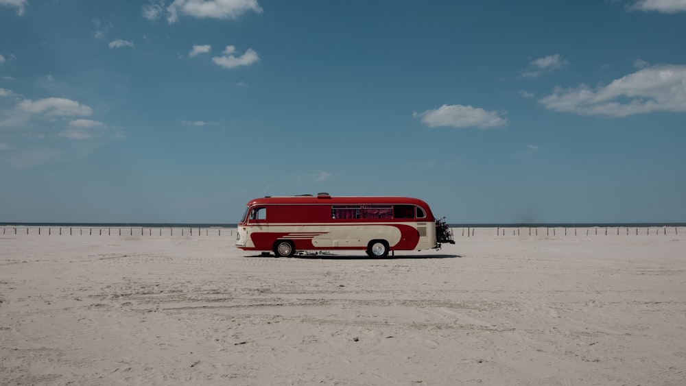 Un autobús rojo y blanco estacionado en la playa