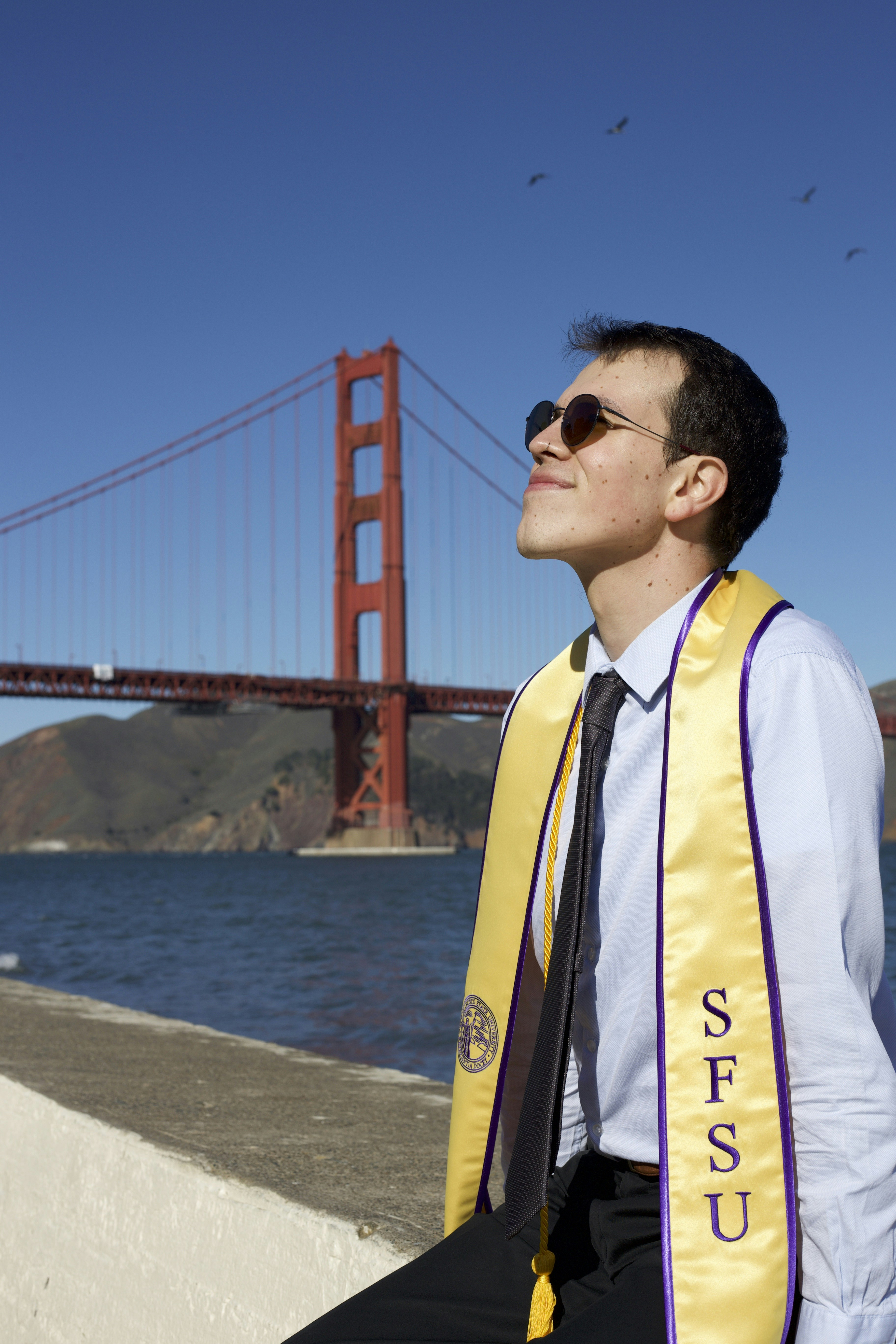 a man wearing a scarf and sunglasses near the water
