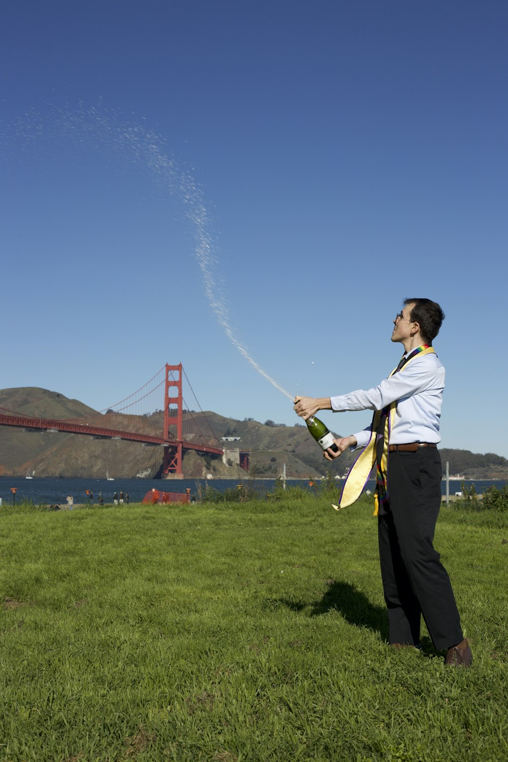Un uomo che tiene una bottiglia di vino davanti al Golden Gate Bridge