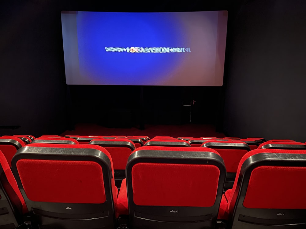 a theater with red seats and a projector screen