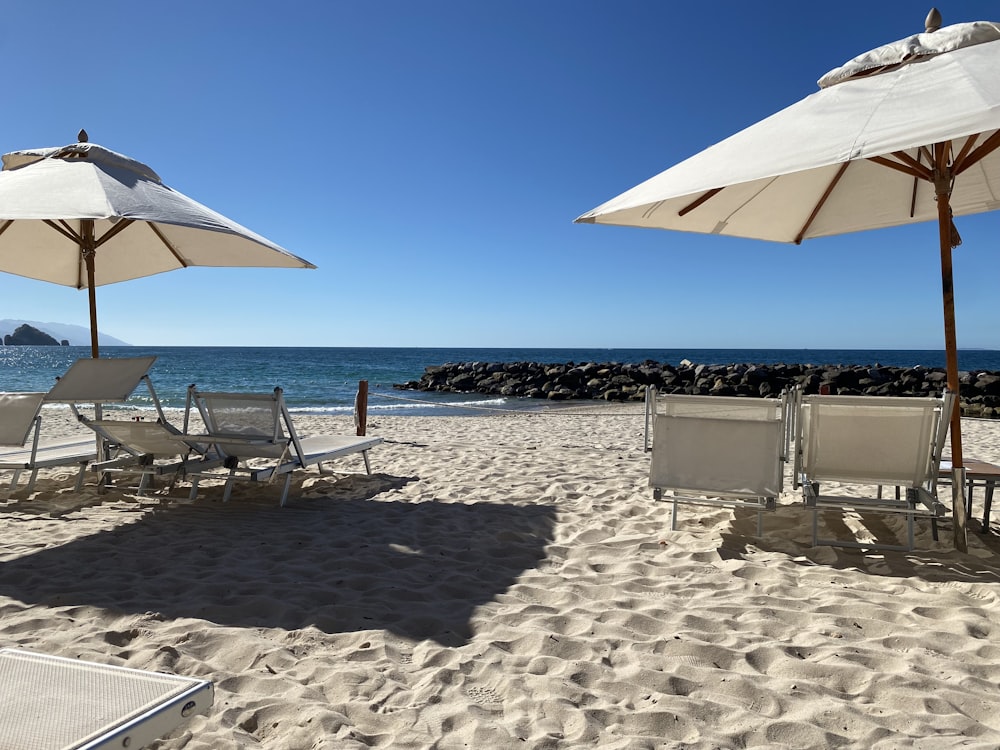 ein paar Liegestühle sitzen auf einem Sandstrand