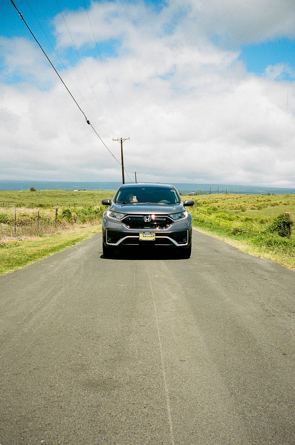 a car driving down a road next to a field