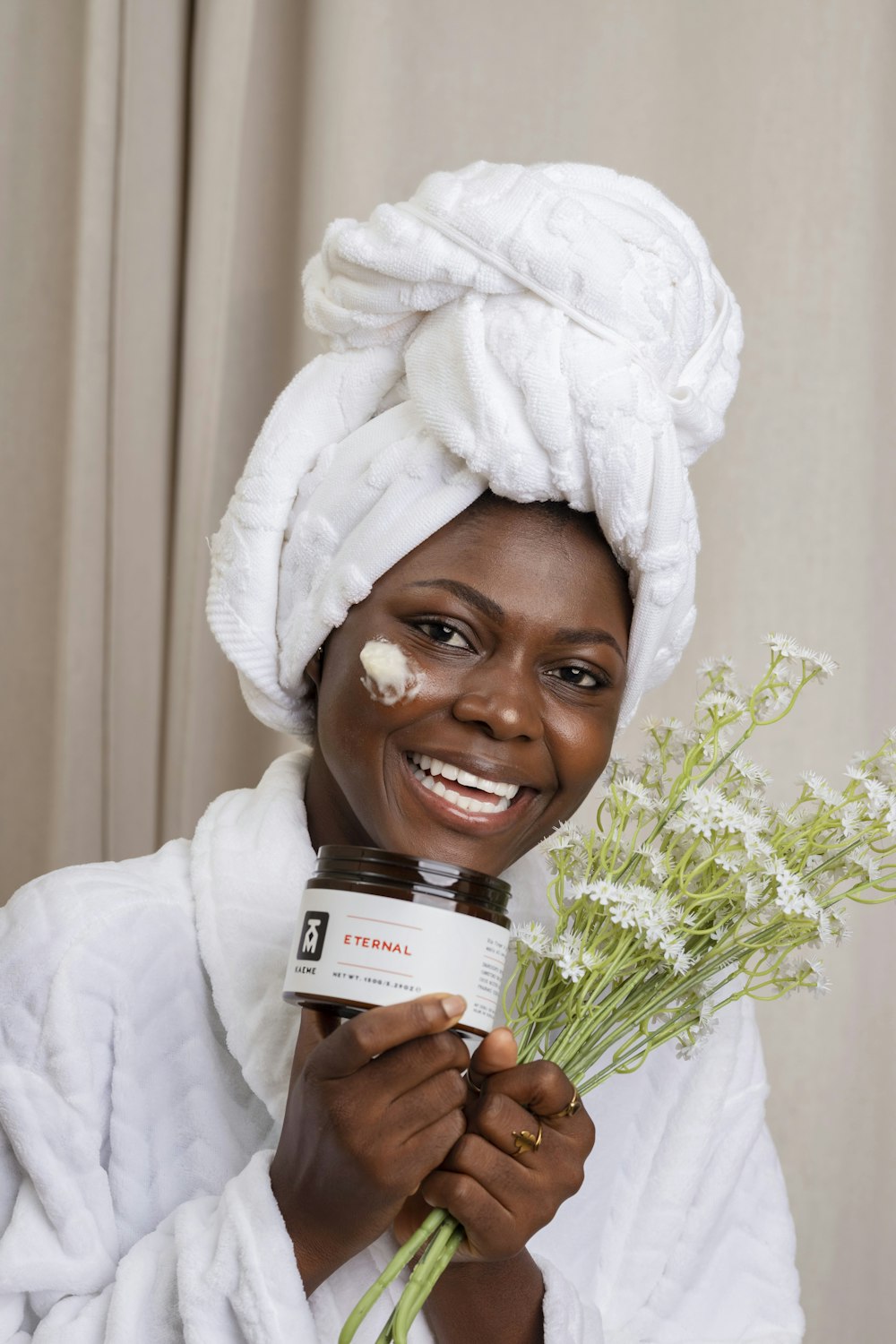 a woman with a towel on her head holding a jar of cream