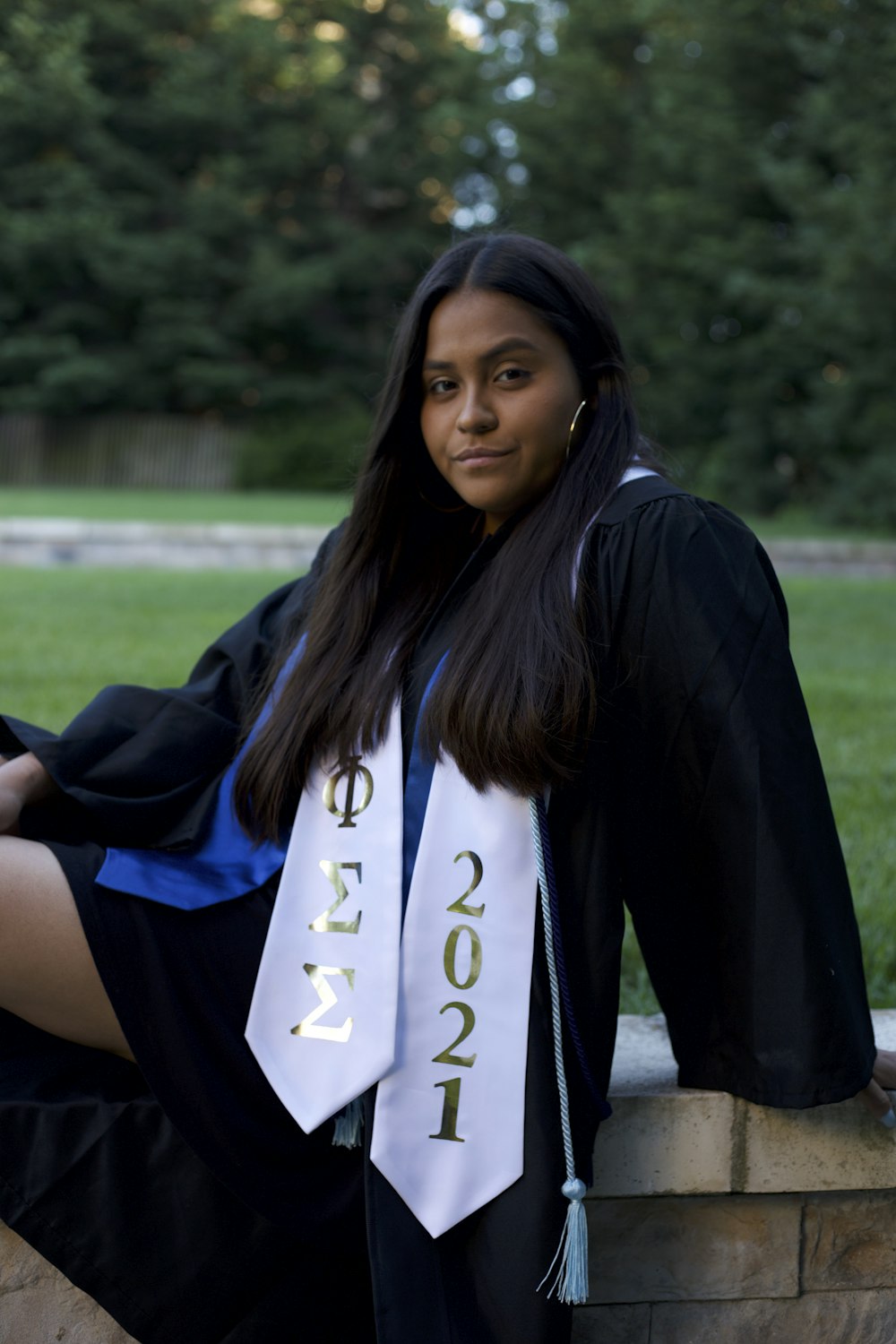 a woman in a graduation gown sitting on a ledge