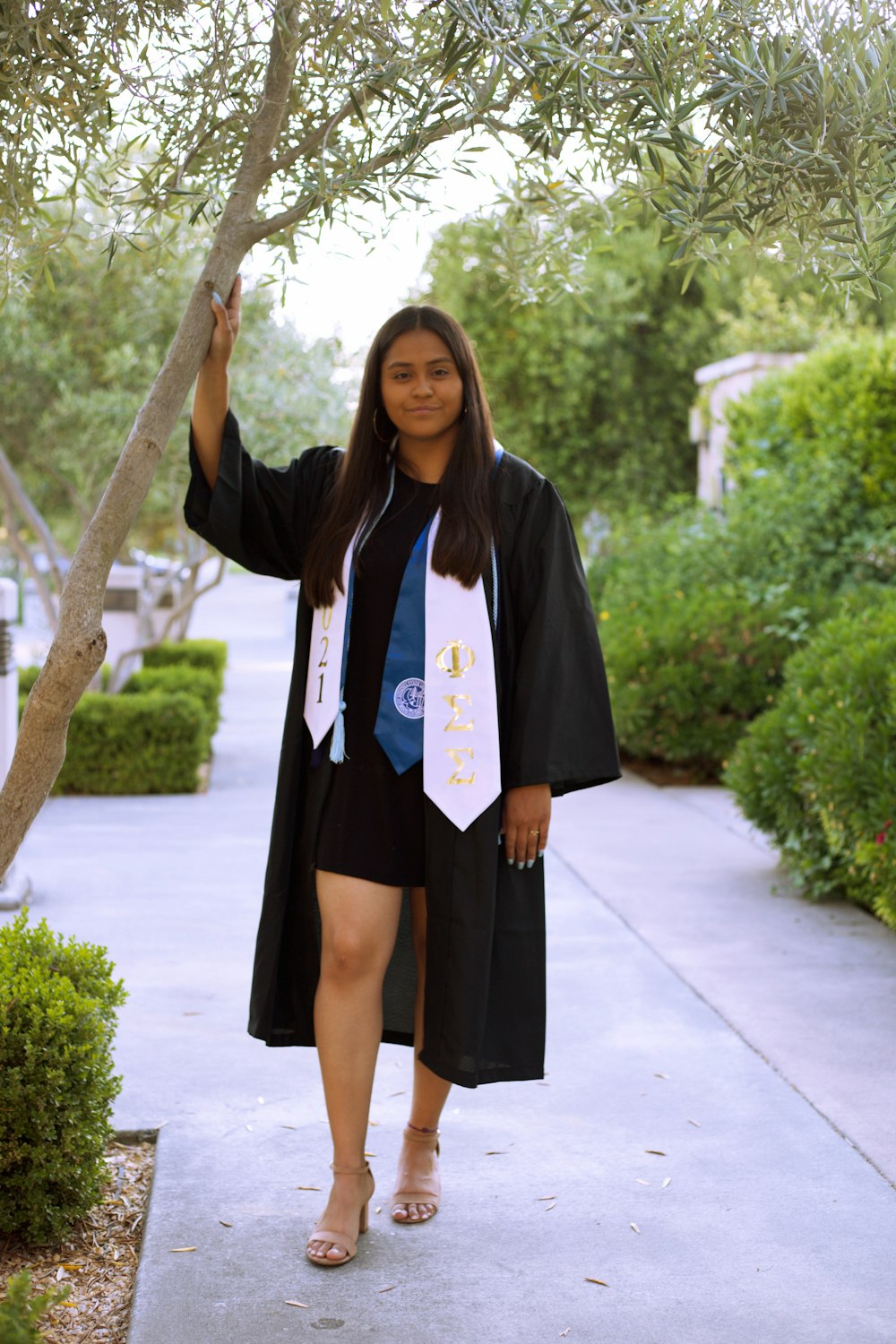 a woman in a graduation gown is walking down a sidewalk