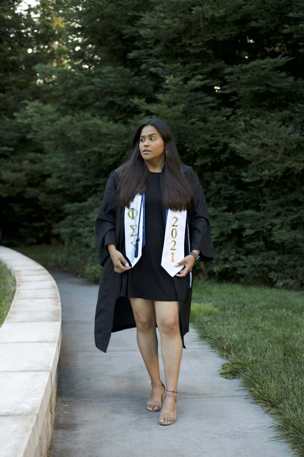 a woman in a graduation gown walking down a sidewalk