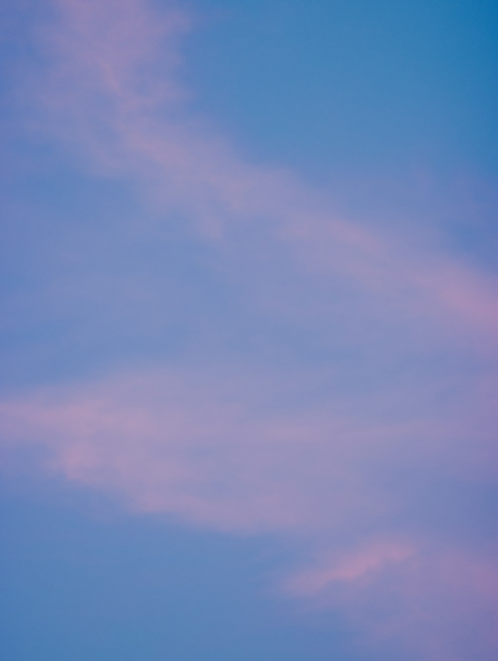 a plane flying in the sky with a pink cloud