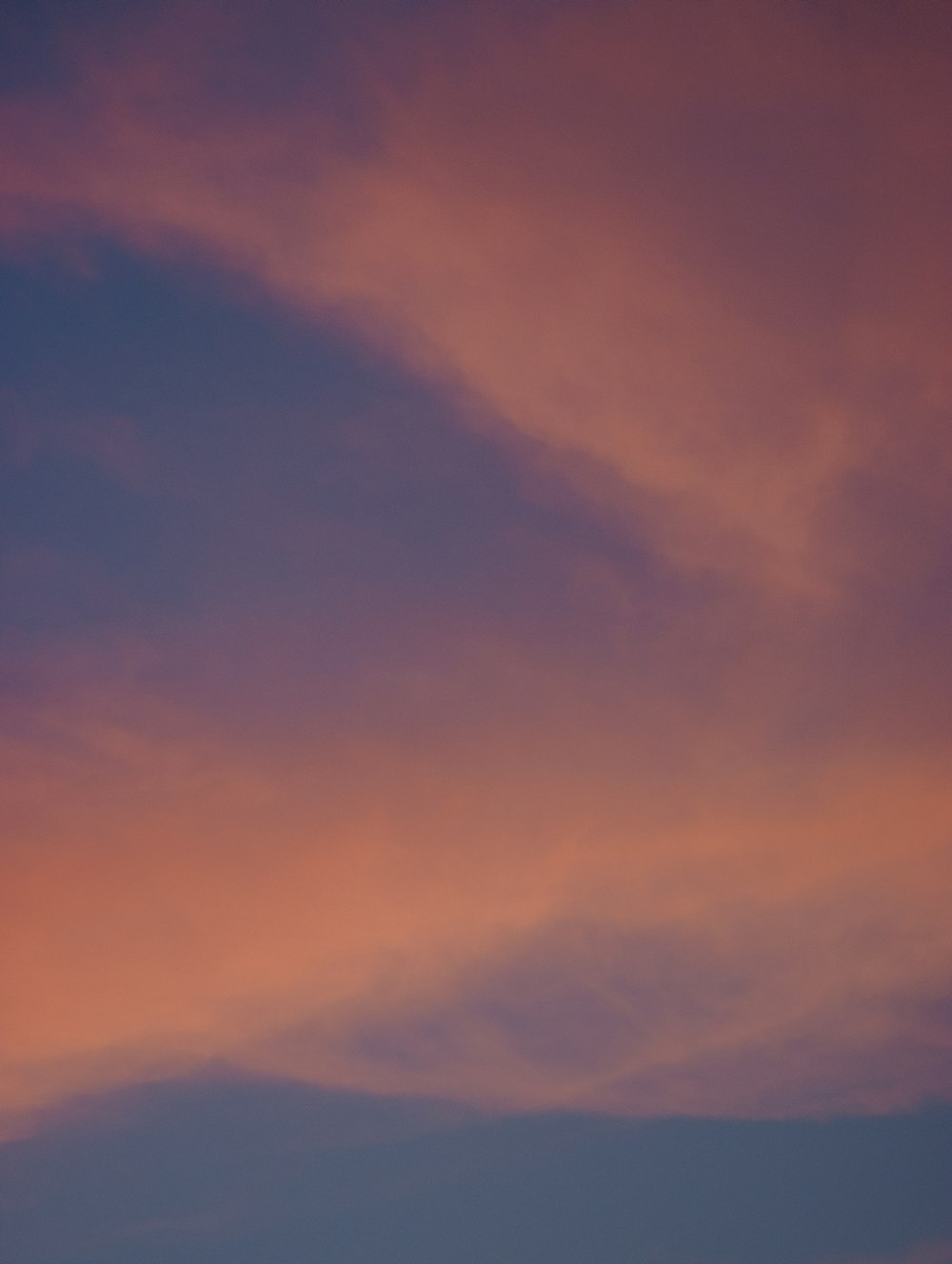 a plane flying in the sky at sunset