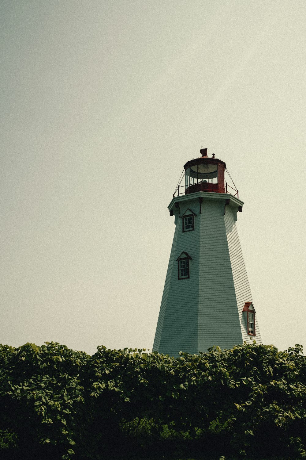 a white lighthouse with a red top on a clear day