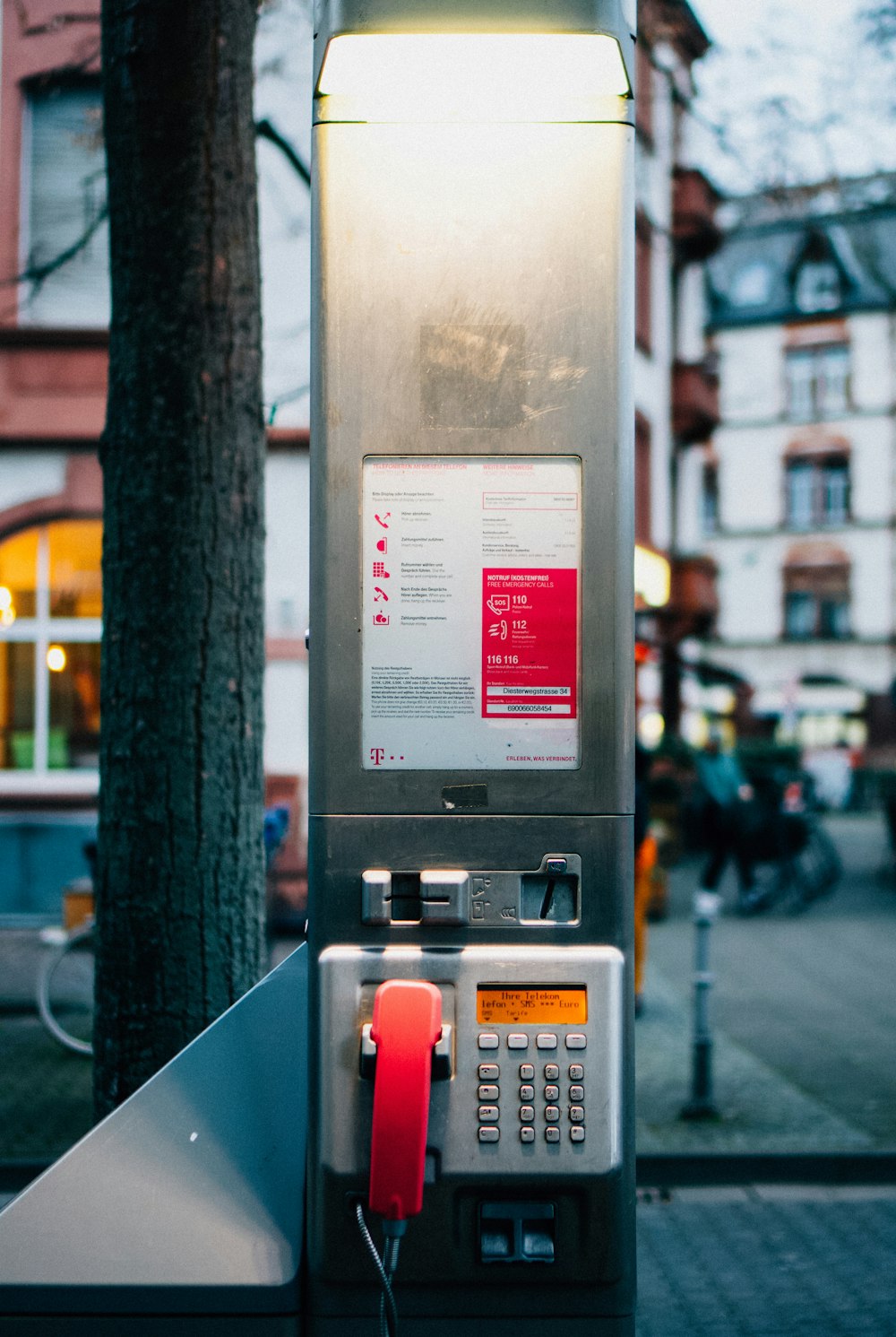 Un teléfono público sentado encima de un poste de metal