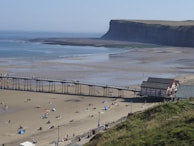 a group of people on a beach near a pier