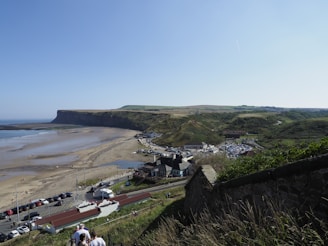 a group of people walking up a hill next to a beach
