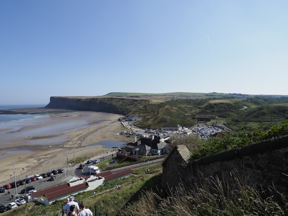 a group of people walking up a hill next to a beach